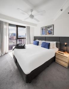 布里斯班Oaks Brisbane on Felix Suites的卧室配有带蓝色枕头的大型白色床