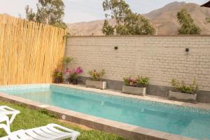 谢内吉亚区Hermosa casa de campo con piscina en Cieneguilla的庭院内的游泳池,配有两把椅子和围栏
