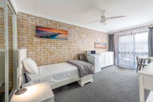 巴利纳海岸汽车旅馆的一间砖墙卧室和一张位于客房内的床