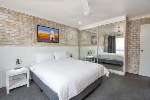 巴利纳海岸汽车旅馆的卧室配有白色的床和砖墙