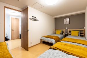大阪Furinkyo・楓林居 7号館的黄色毯子的客房内的两张床