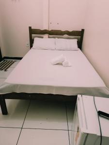 邦热苏斯-达拉帕Hotel e Lanchonete Bom Gosto的配有白色床单和枕头的宿舍间内的一张床位