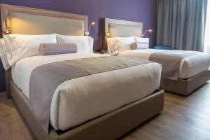 瓜达拉哈拉Sheraton Guadalajara Expo的紫色墙壁的酒店客房内的两张床