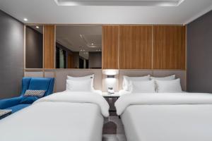 堤川市Jecheon The Wall Hotel的一间设有两张床和一张蓝色椅子的房间