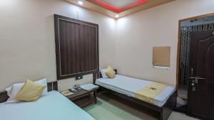 加雅Hotel Shakuntla Palace的小房间设有两张床和一扇门