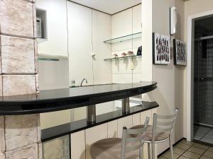 圣路易斯Flat number one temporadalitoranea的厨房配有白色橱柜和带2把椅子的柜台。