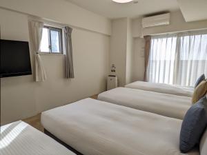 大阪ESLEAD HOTEL Namba South Ⅲ的酒店客房设有三张床和电视。