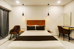 海得拉巴Rcc Hotel Banjara Hills的卧室配有一张床和一张桌子及椅子
