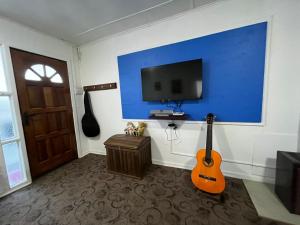 蓬塔阿雷纳斯Casa的配有电视和墙上吉他的房间