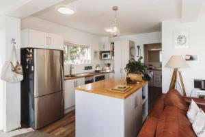 新普利茅斯Te Moana Waterfront的厨房配有白色橱柜和不锈钢冰箱