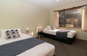 新普利茅斯Beachfront Bliss On Wanaka Terrace Support Local的一间卧室设有两张床和窗户。