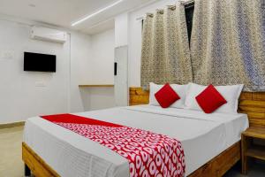 浦那OYO Hotel Paradise的一间卧室配有一张带红色枕头的大床