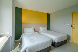 帕夭พิลโล่ อินน์ พะเยา Pillow Inn Phayao的两张床位于带绿色和黄色墙壁的客房
