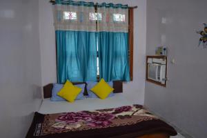 克久拉霍Hostel shivshakti khajuraho的客房设有带蓝色窗帘的床和窗户。