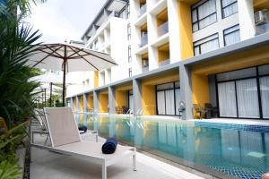 奈通海滩Wyndham Garden Naithon Phuket的酒店游泳池设有椅子和遮阳伞