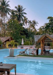 爱妮岛El Nido Moringa Resort的一个带椅子和桌子的度假村游泳池