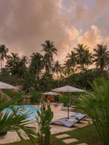 爱妮岛El Nido Moringa Resort的一个带遮阳伞和棕榈树的度假游泳池