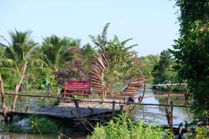 金瓯Bungalow - Farmstay Hoa Rừng U Minh的一条河上桥上的红长椅