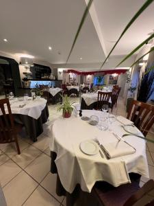 贝努维尔Hôtel Bien Être La Glycine的用餐室配有带白色桌布的桌子