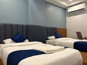 卡努尔KKM Highlands的酒店客房,配有3张带蓝色枕头的床