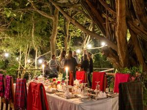 阿鲁沙Mount Meru Game Lodge & Sanctuary的一群人站在桌子旁,灯火通明