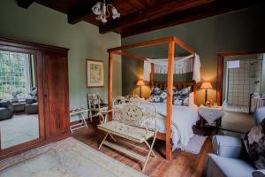 斯韦伦丹Moolmanshof 1798, Traditional Cape Dutch H-Shaped Farmhouse的一间带天蓬床的卧室和一间客厅