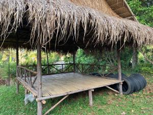 Ban Khao Ya Nuaลาน​กางเต๊นท์​ข้าวซอย​เขาค้อ​的茅草屋顶和木制平台的小屋