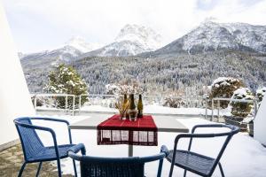 施库尔Chasa Tulai F83的雪覆盖的山景阳台上的桌椅