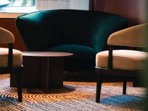 里尔诺沃特里尔中央格兰德广场酒店的两张椅子、一张桌子和一张绿色沙发