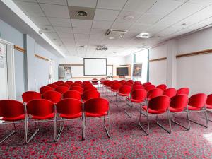 马赛马赛市中心圣查尔斯火车站宜必思酒店的一间会议室,配有红色椅子和屏幕
