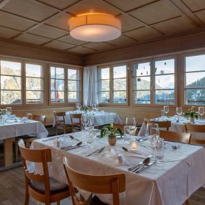 Wergenstein魔羯酒店餐厅的一间设有白色桌椅和窗户的用餐室