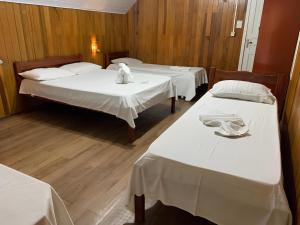 博尼图查莱公寓酒店的一间设有三张床的房间,配有白色床单和泰迪熊