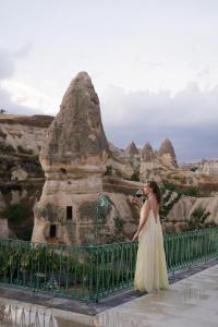 格雷梅Aza Cave Cappadocia Adult Hotel的站在一座桥上,站在一座山的黄色连衣裙上的女人