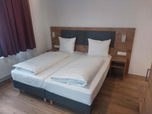 格尔斯托芬斯特恩宾馆的一张带两张白色床单和木制床头板的床