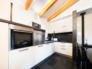 CelaHoliday Home Conceição - NZE221 by Interhome的厨房配有白色橱柜和黑色家电