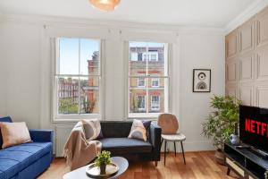 伦敦Delightful Flat in London - Sleeps 6的客厅设有蓝色的沙发和2扇窗户。