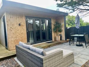 布里斯托1 bedroom rural cabin retreat with hot tub in Hambrook close to Bristol city centre的平台上设有带沙发和桌子的庭院