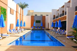 开罗Moon Light Hotel Cairo DAR EL ESHARA的一个带椅子和蓝伞的游泳池