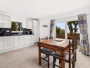 普尔赫利Seaborne Cottage的厨房配有白色橱柜和木桌及椅子