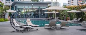 新加坡Fraser Suites Singapore的一座带椅子和遮阳伞的游泳池位于一座建筑旁边