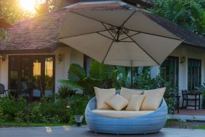 清迈Le Baan Thai Boutique Villa的度假屋前设有带枕头的椅子和遮阳伞