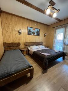 斯拉夫西克Zarichna Lyks的一间带两张床铺的卧室,位于带木墙的房间内