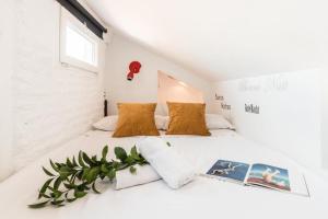 马德里Charming La Latina Home的一间白色卧室,配有一张带书籍的床