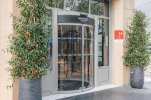 巴黎Appart'City Collection Paris Gare de Lyon的通往两座盆栽植物的建筑物的旋转门