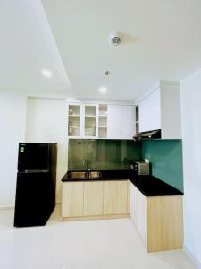 顺安Experience Luxury Living! Spectacular 1-Bedroom Apartment in Thuan An, Binh Duong的厨房配有黑冰箱和白色橱柜。