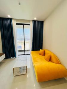 顺安Experience Luxury Living! Spectacular 1-Bedroom Apartment in Thuan An, Binh Duong的一张黄色沙发,位于带大窗户的房间里