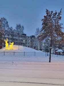 罗瓦涅米Arctic Apartment with own Sauna的两个黄色雕塑在雪覆盖的公园里