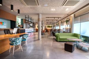 科多维拉潘普洛纳客床酒店的大堂设有绿色的沙发和桌椅