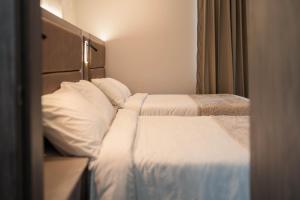 巴兰基亚Amari Living Suites的配有2张床铺的酒店客房,提供白色床单和枕头