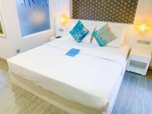 马富施Velana Beach Hotel Maldives的一间卧室配有两张带白色床单和蓝色枕头的床。
